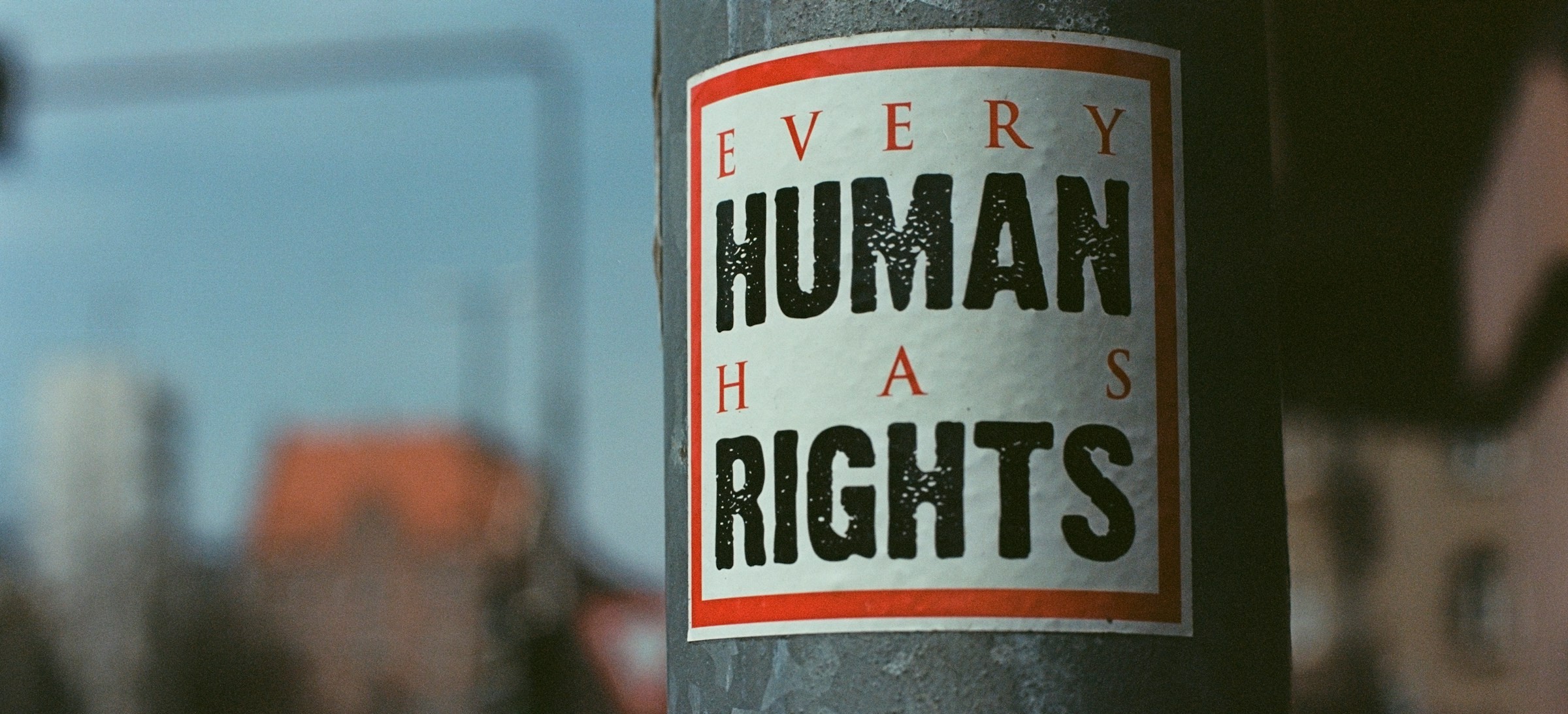 A sticker on a signpost reading "Every Human Has Rights"